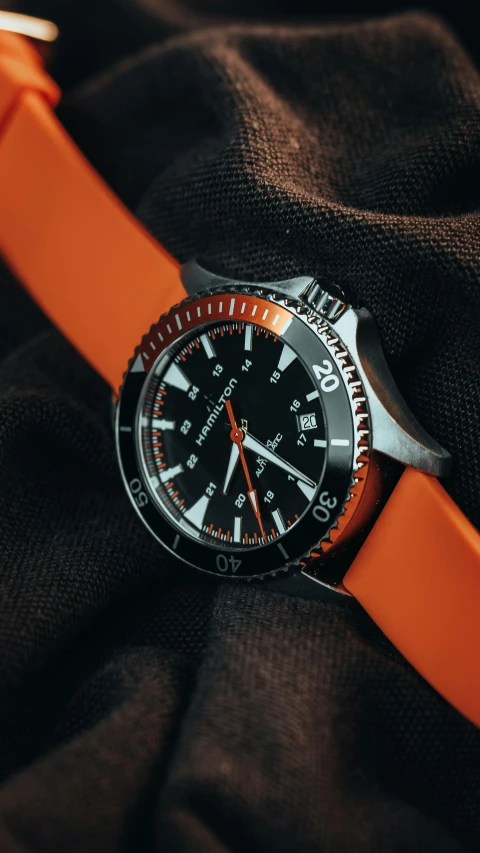 an orange watch on top of black fabric