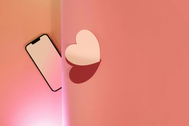 an iphone and heart sticker on a pink wall