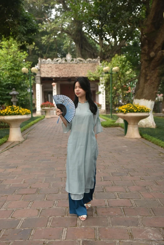 a beautiful woman holding an umbrella on top of a brick walkway