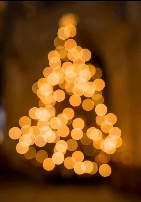 blurred blurry pograph of a lit christmas tree in an indoor building