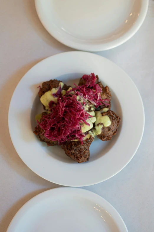 a white plate topped with meat next to another plate of food