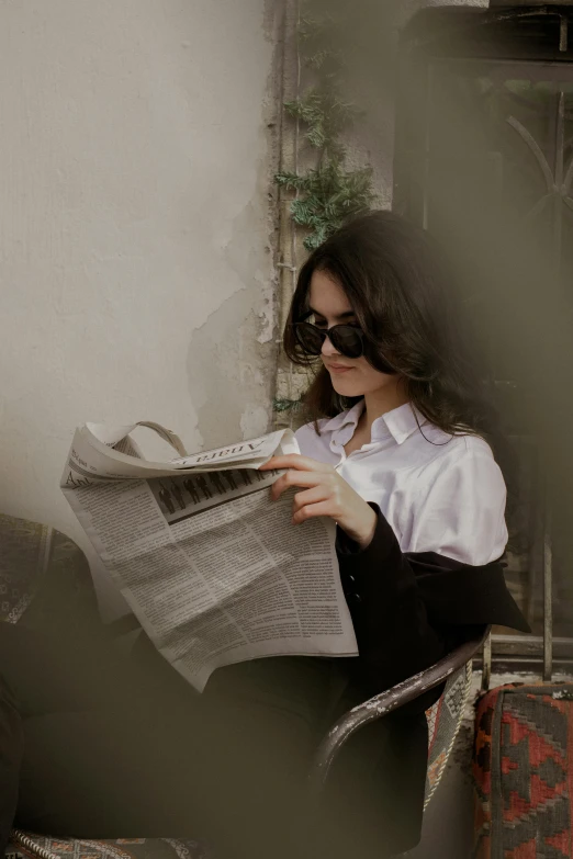 a young woman reading the newspaper on a balcony