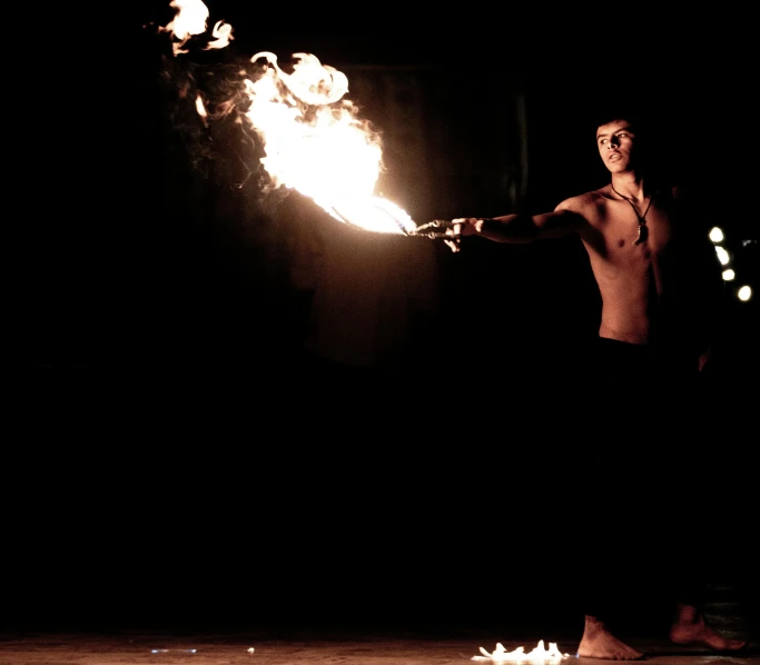 a man holding a fireball while standing in the dark