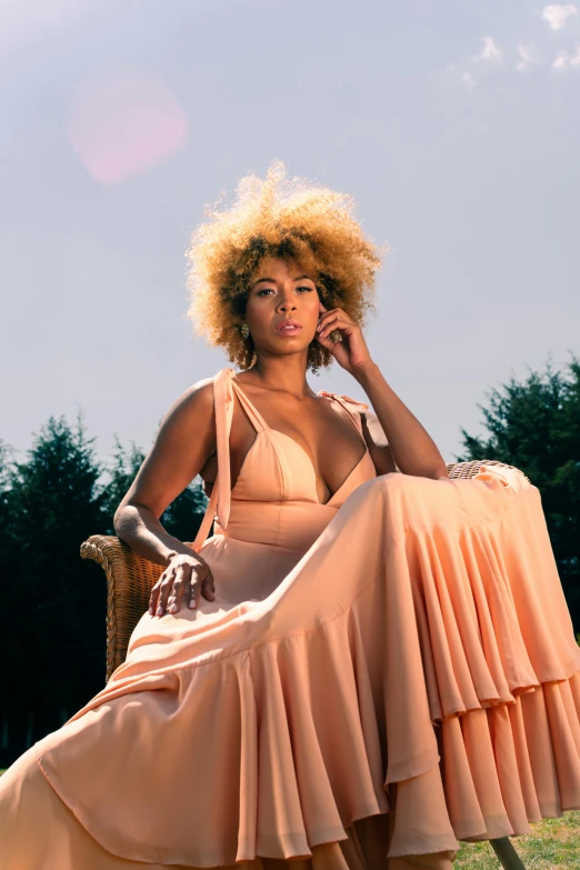 a woman with an afro sitting on a chair in a yard talking on a cell phone