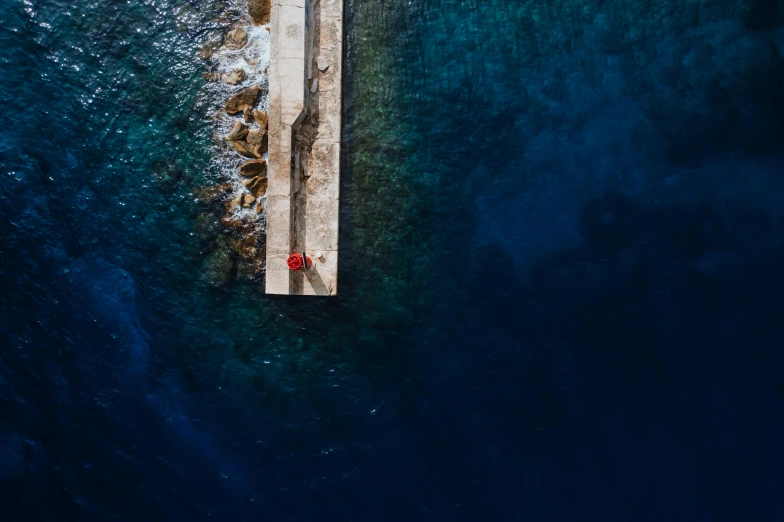 an aerial s of two people walking across a bridge over water