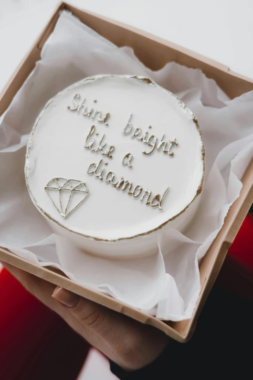 a cake is displayed in a box with white paper and writing