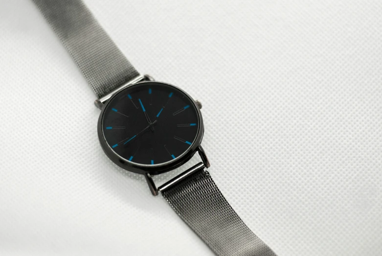 a blue face watch sits on a gray mesh strap