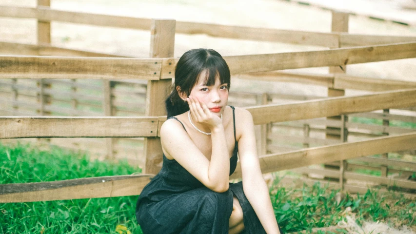 a woman is sitting in the grass wearing a dress