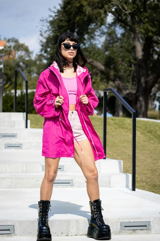 a woman in pink standing on steps with her hands behind her back