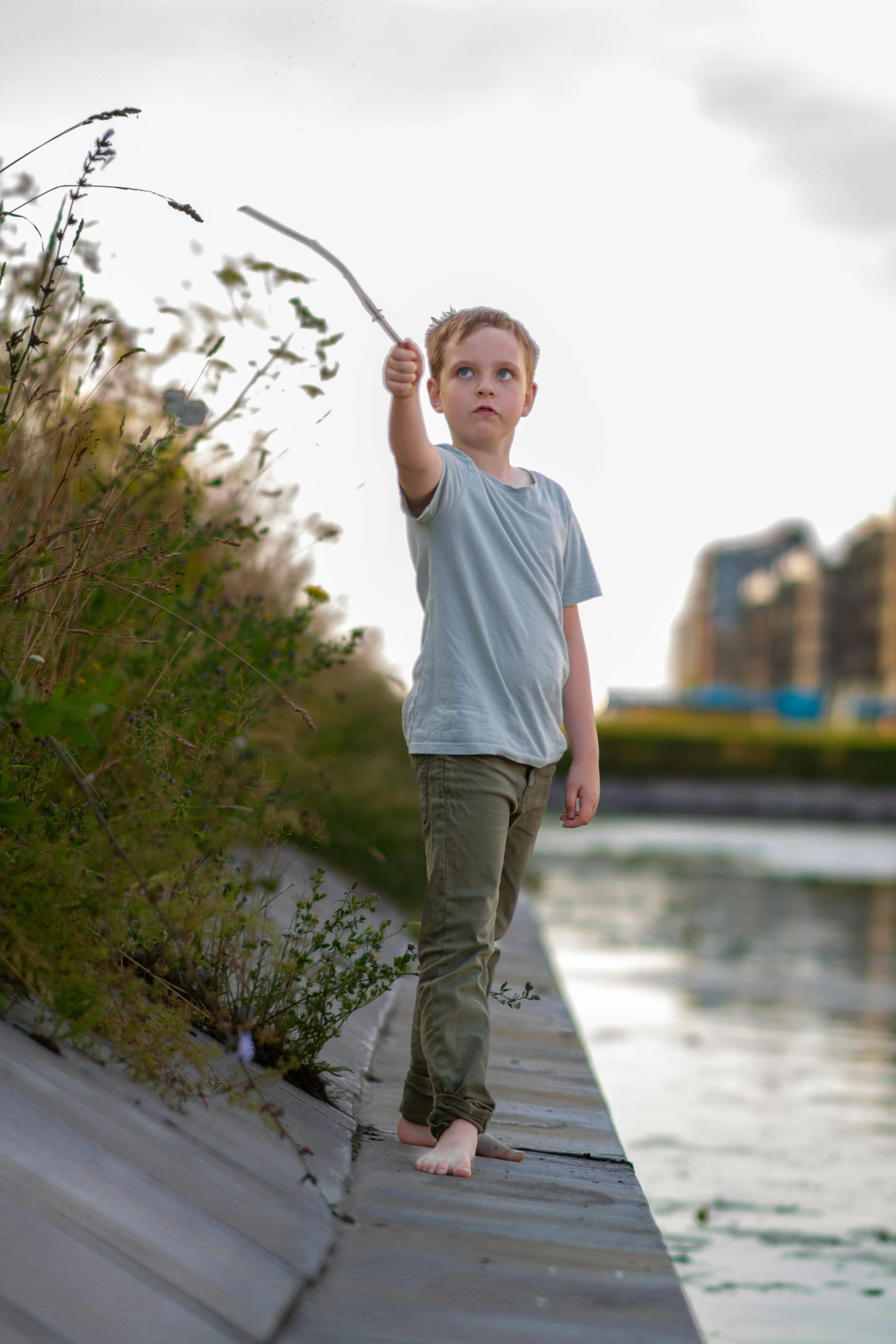 a boy standing on a pier with a fishing pole