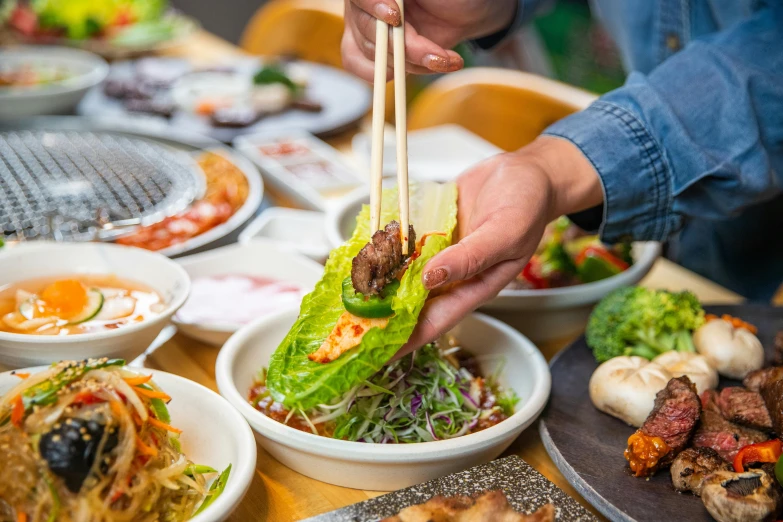 a person putting chopsticks into a salad in a bowl