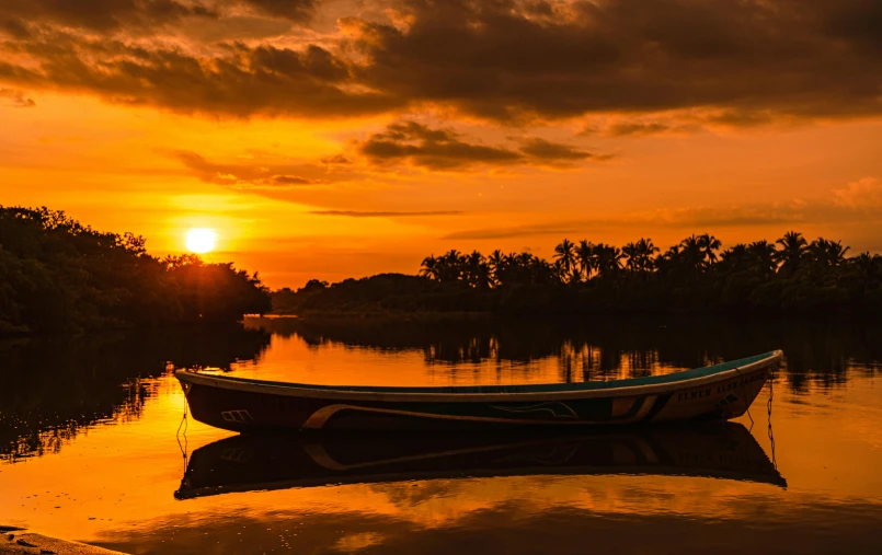 an empty boat sits in the river as the sun rises