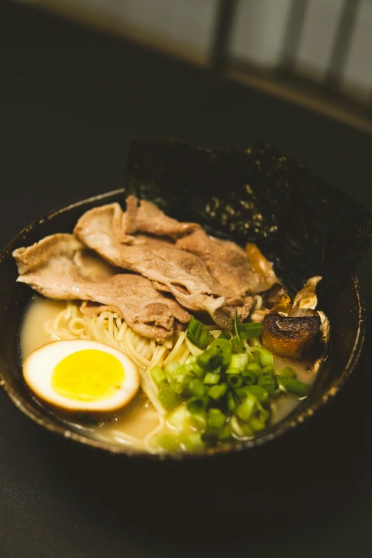 a bowl with various food items such as meat and egg on the side