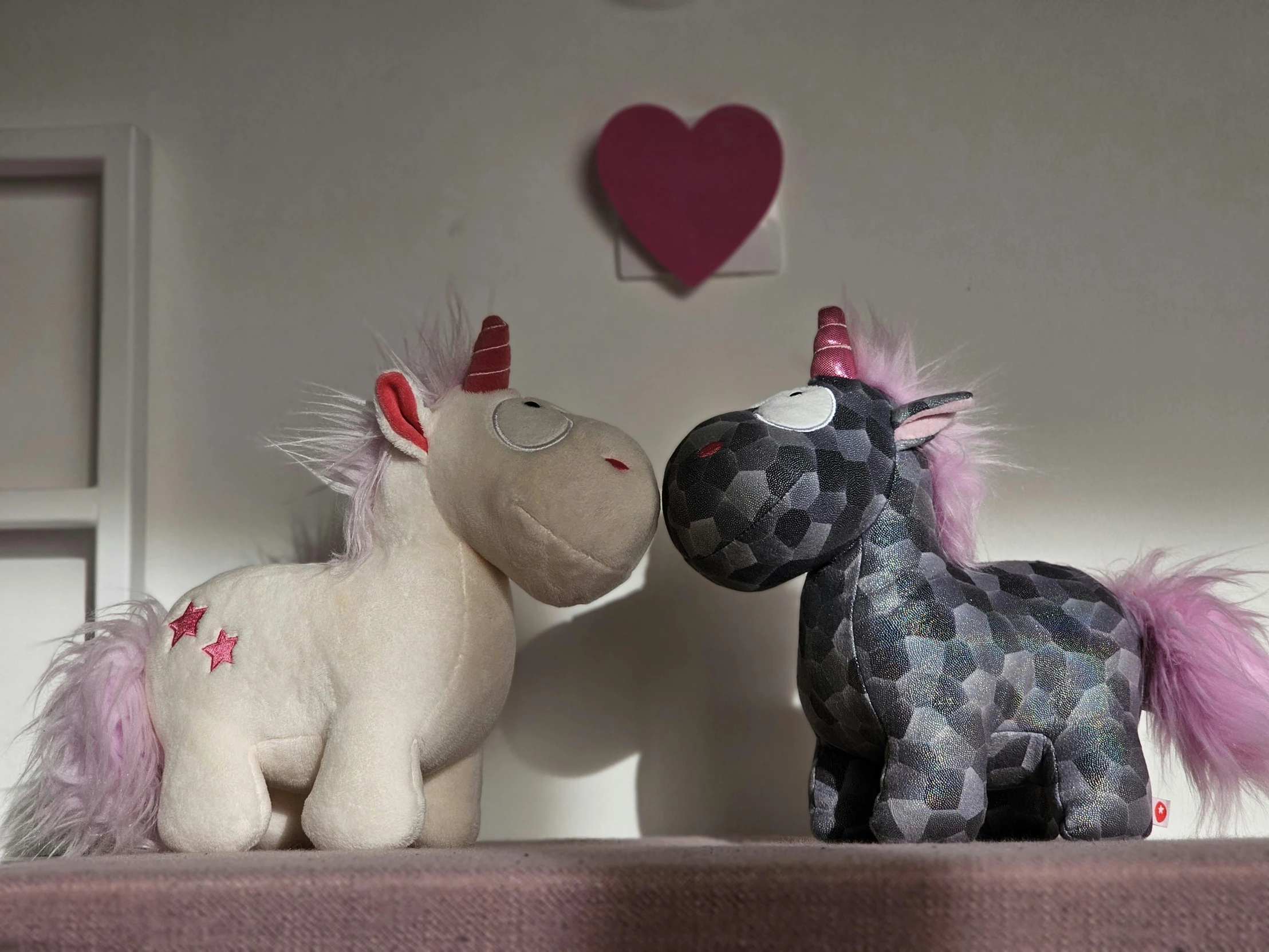 two stuffed toys on a shelf near one another