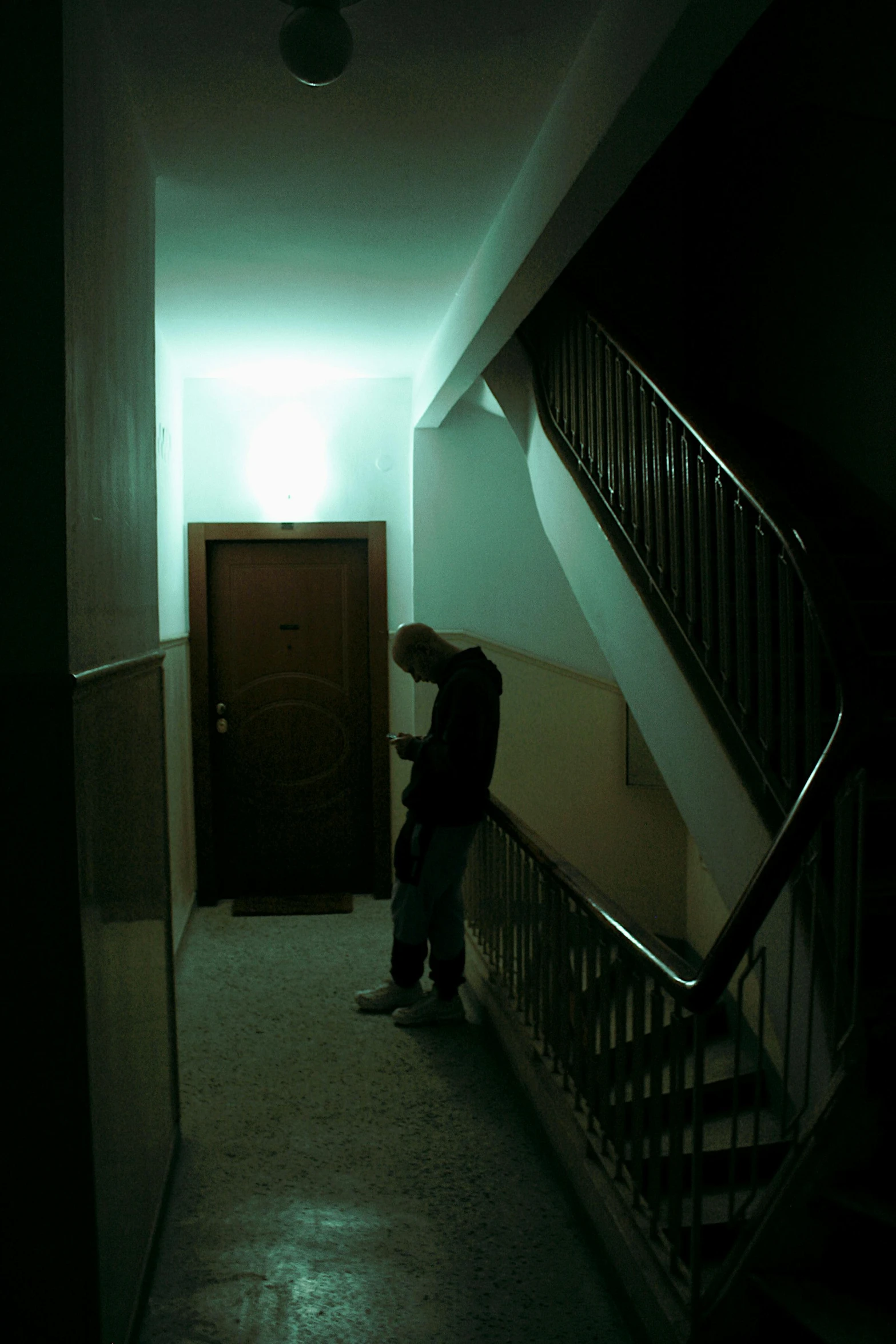 a person stands in a long hallway next to a staircase