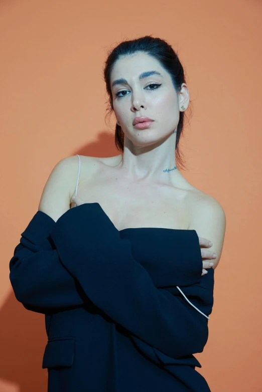 a woman standing in front of an orange wall with her arms crossed