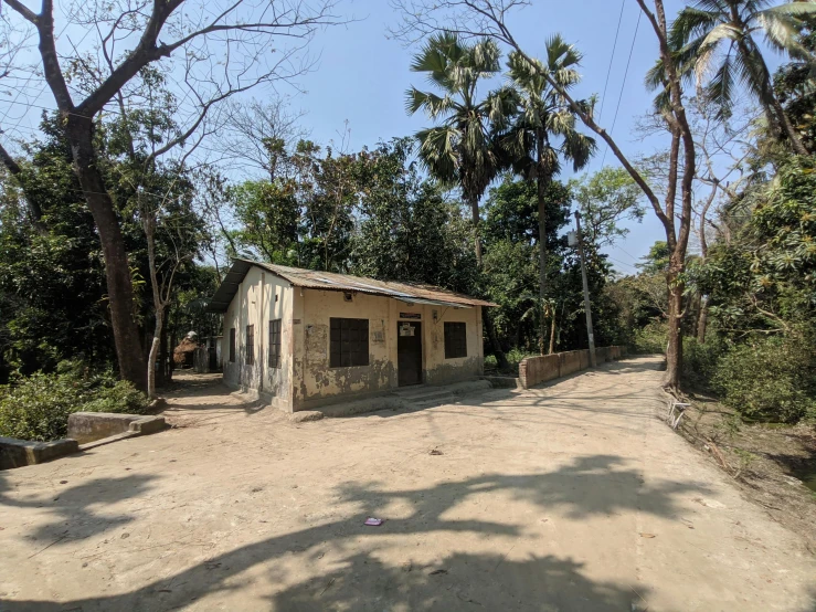 an empty building with no doors sits on the dirt near trees