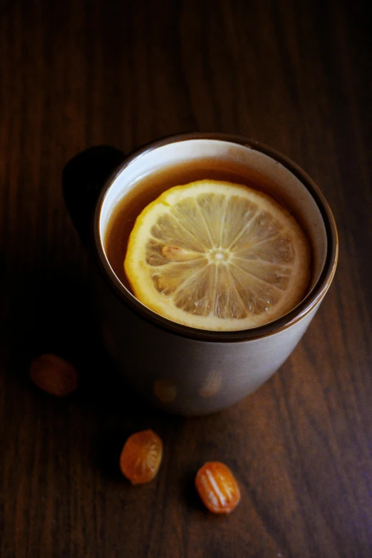 a cup filled with lemon slices sitting next to nuts