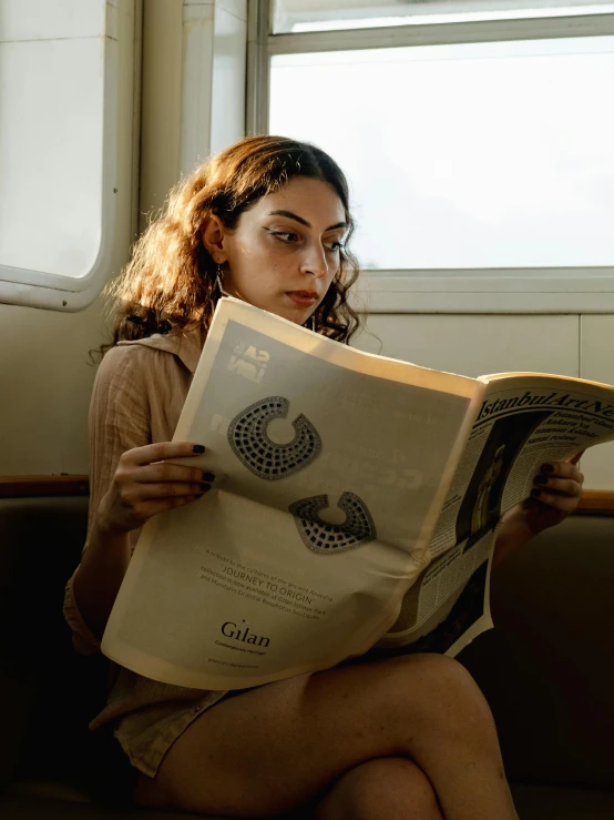 woman reading newspaper sitting by window on subway