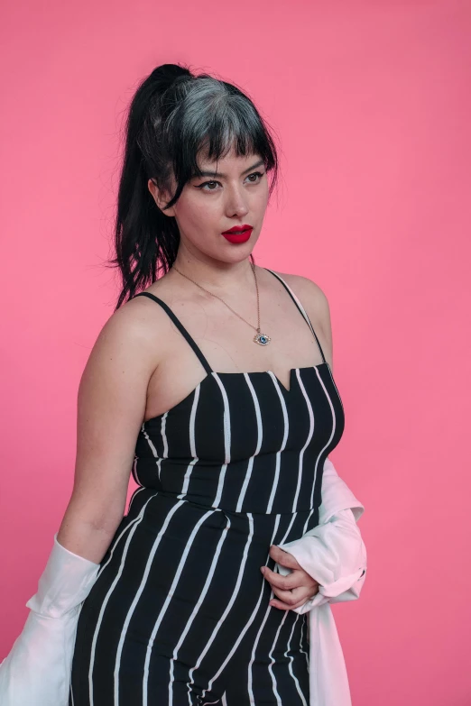 a woman in striped dress against a pink background