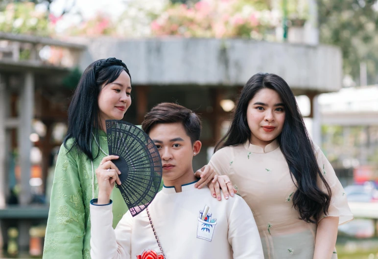 a woman in a green jacket holding a fan with two other people and a man