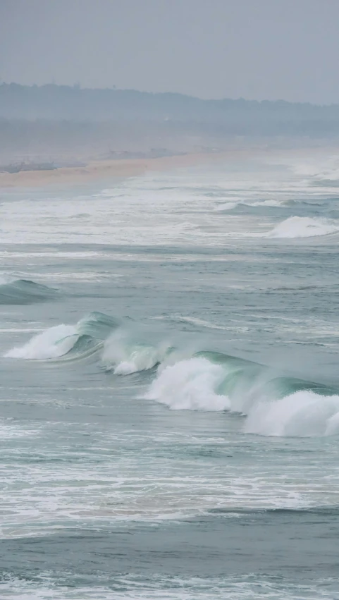 waves crash into the shore during a cloudy day