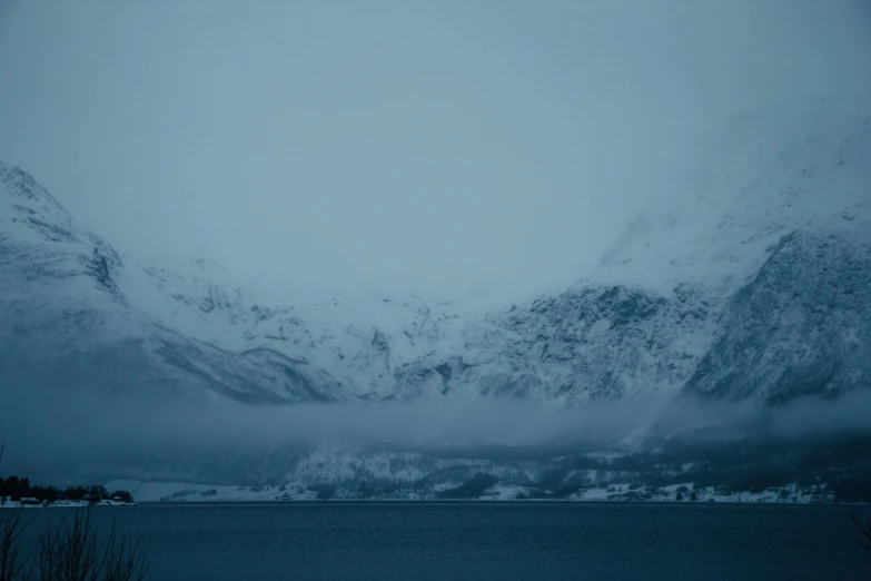 snow covered mountains with blue water in the foreground