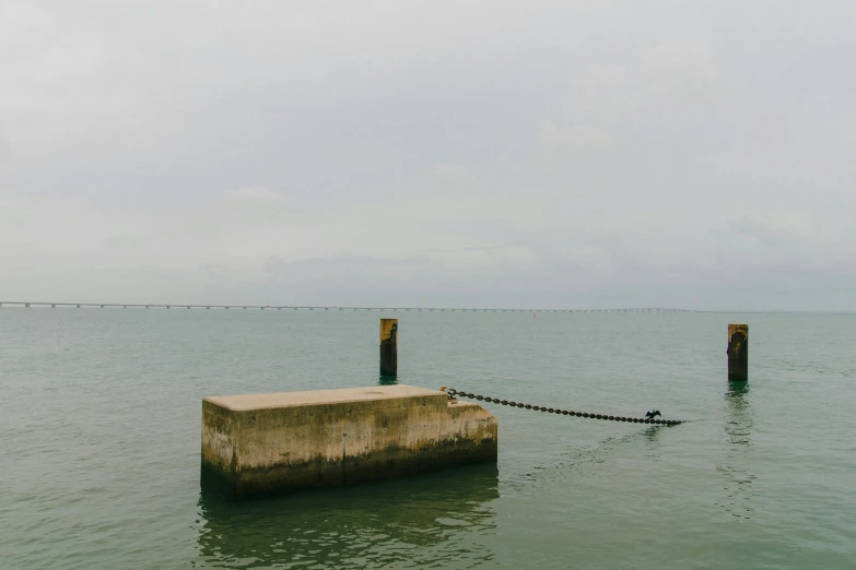 a buoy tied to a concrete post in the water