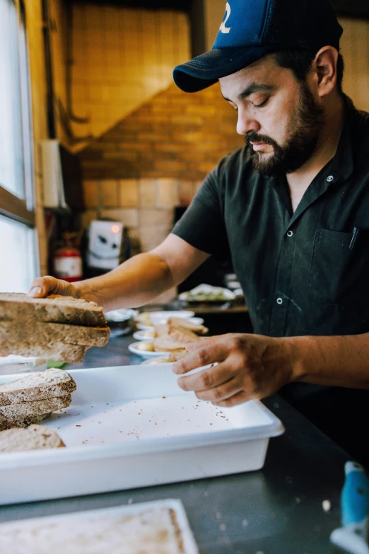 the man is making a sandwich while wearing a hat