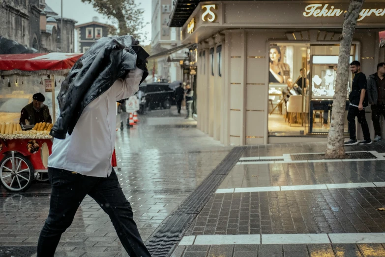 a man in a white shirt is walking on the sidewalk