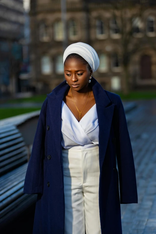 a woman is standing near a bench on a street