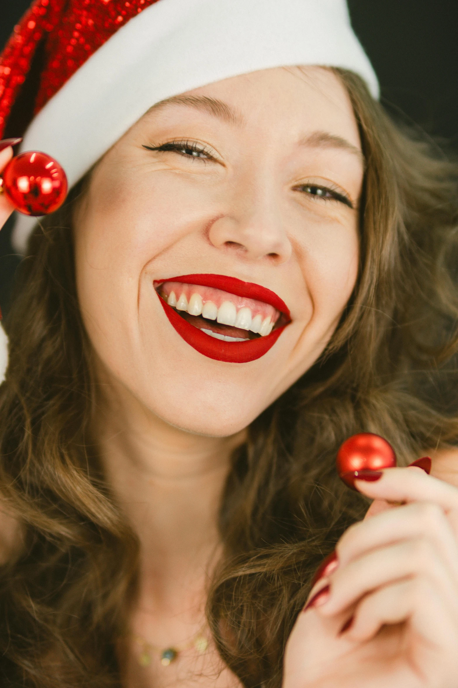 a woman wearing a santa hat and holding a red ornament