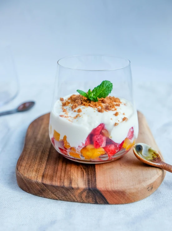 a glass filled with yogurt and fruit next to a spoon