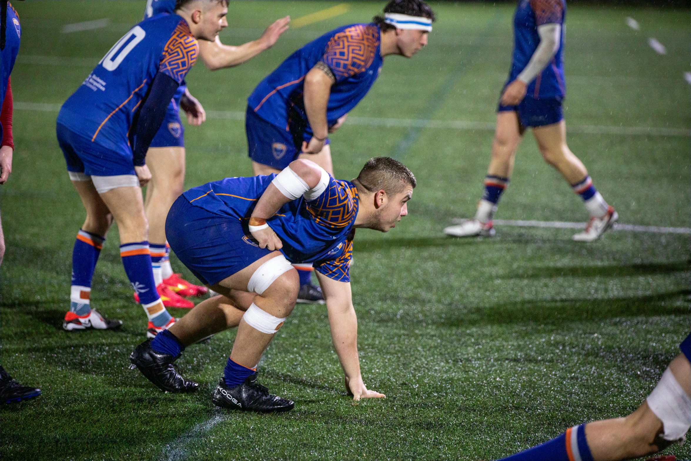 two teams playing rugby in the rain