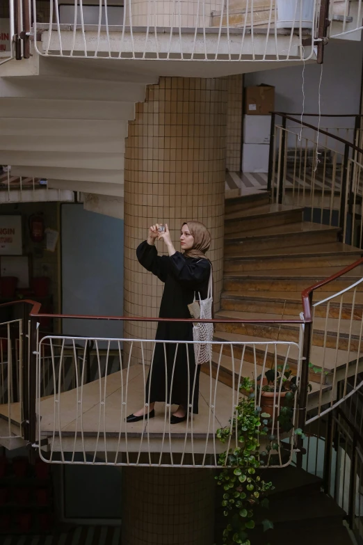 woman taking a po in a building with a large staircase