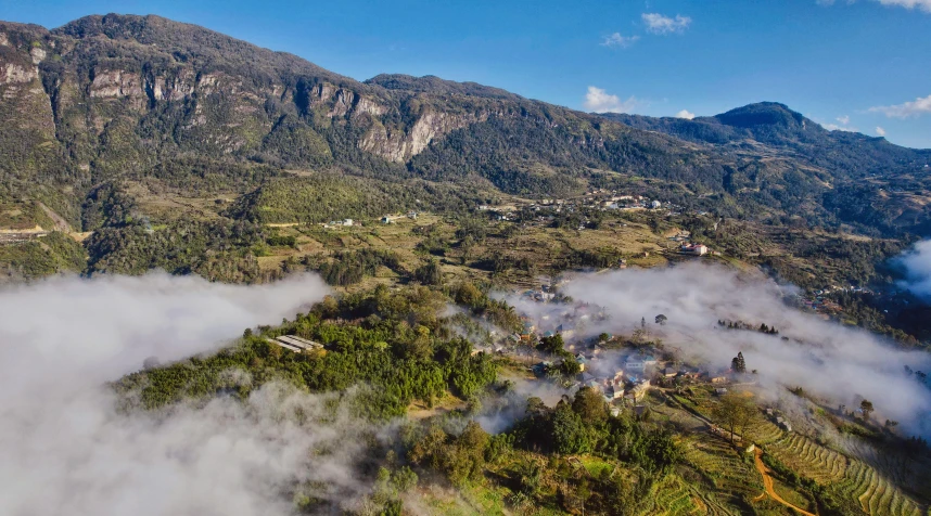 a mountain covered in mist and clouds next to a valley