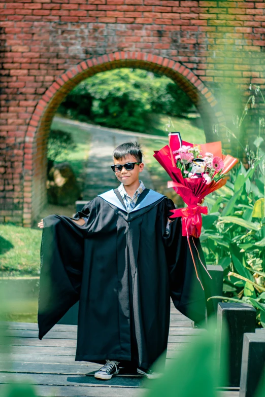 a man is holding onto flowers in a graduation gown