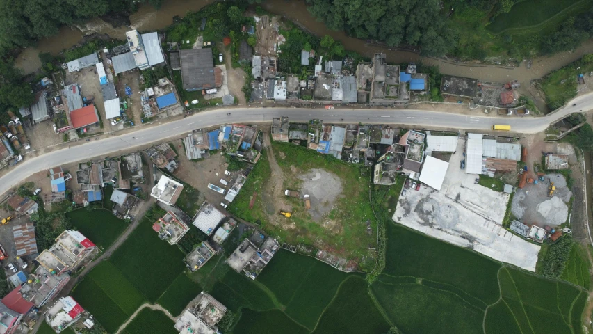 an aerial view of a rural area with a road, a building and a lot of houses