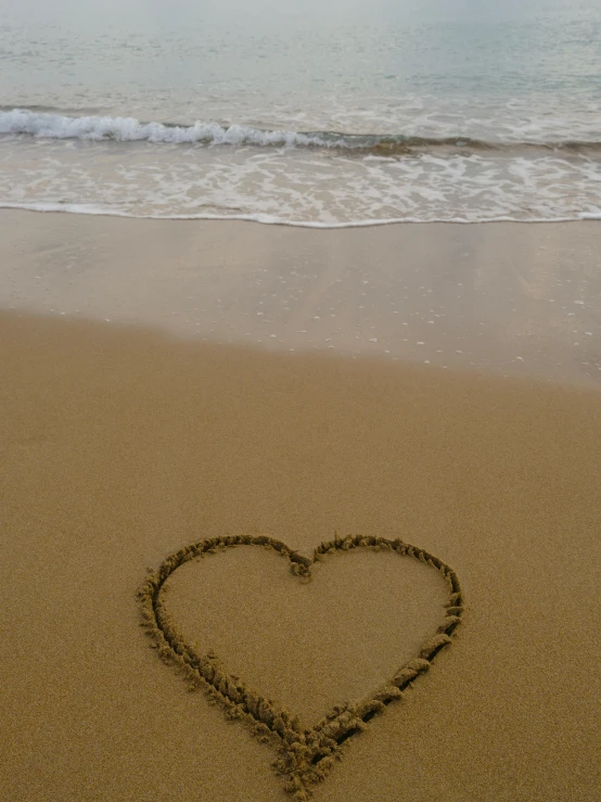 a heart drawn in the sand at a beach