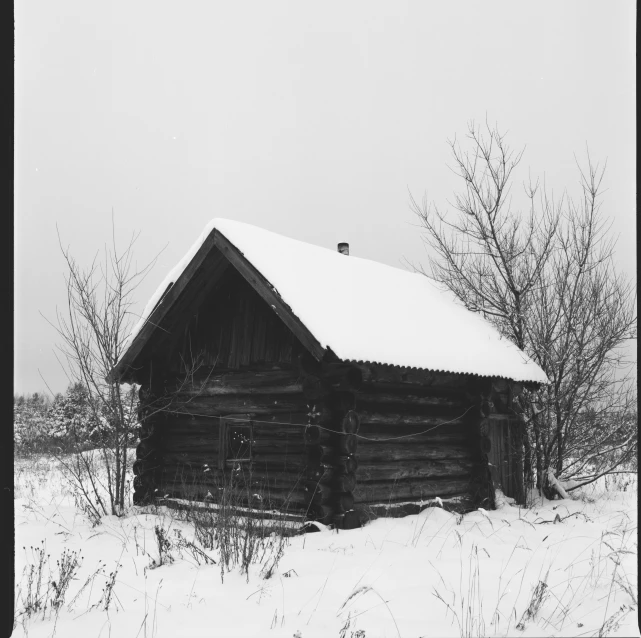 old log cabin covered in snow in winter