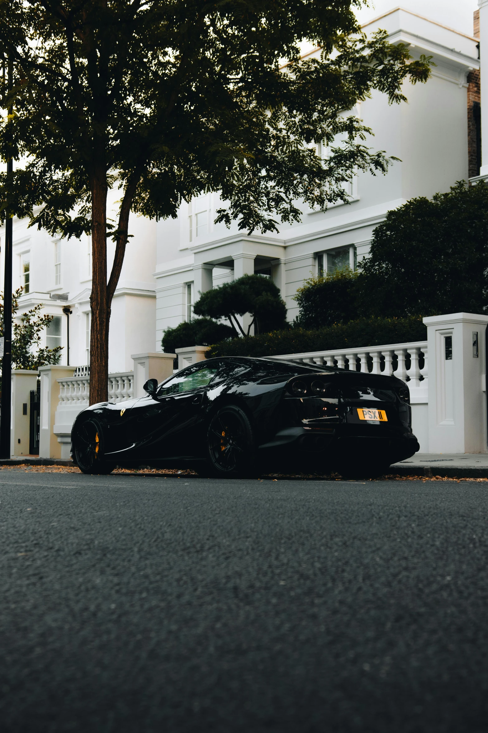 a black car is parked in front of a tree