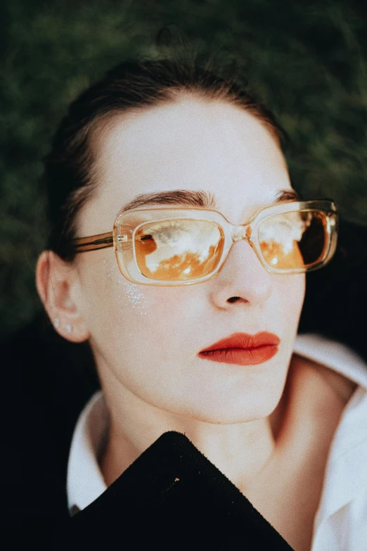 a woman with glasses wearing a white shirt and red lips