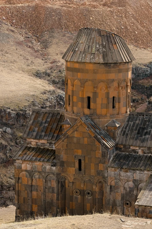 an old building with a steeple near some mountains