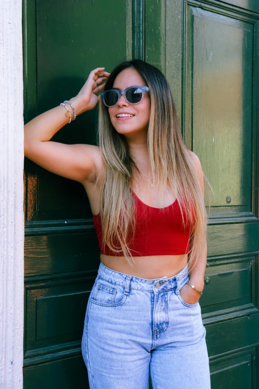 young woman wearing sunglasses standing against the door