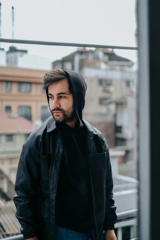 the man is standing near a balcony ledge looking at soing