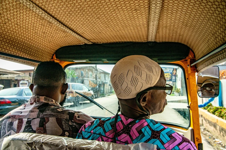 two people sitting inside a vehicle on the side walk