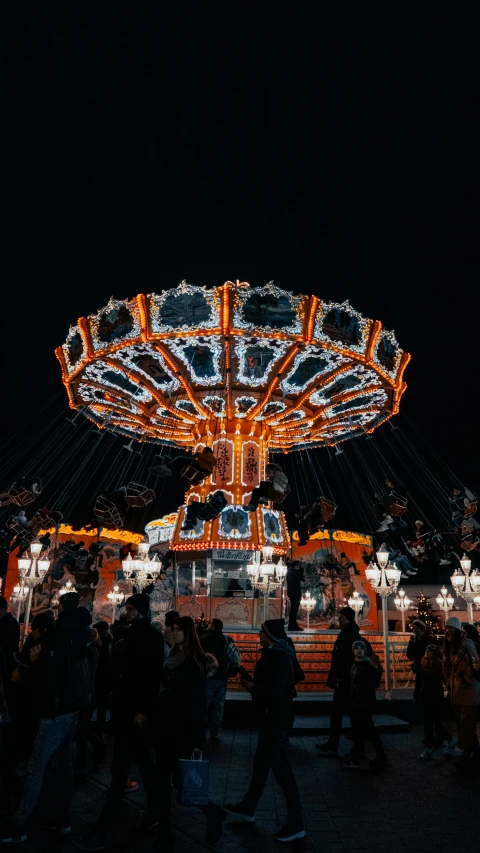 a carnival park at night with people walking around