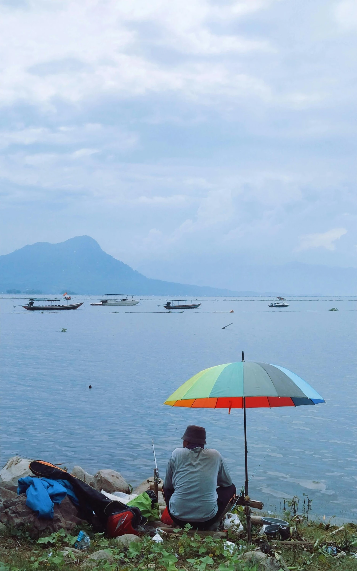 man sitting on the edge of the beach looking at the water