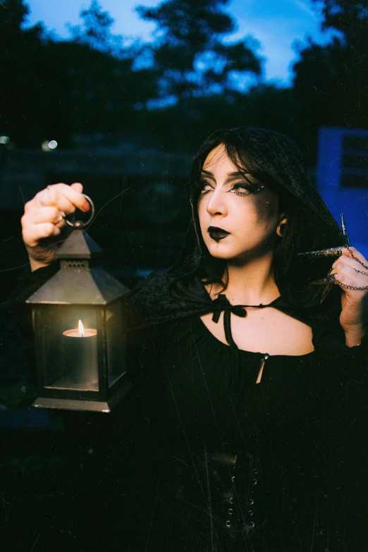 a woman in gothic attire holding a lantern