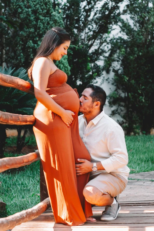 a man kissing a pregnant woman on the cheek